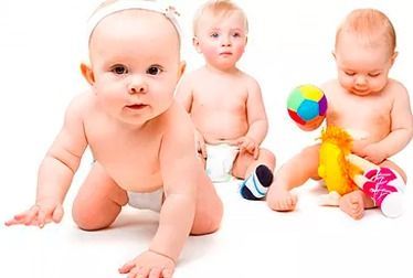 Tres bebés en pañales sobre un fondo blanco, uno gateando, dos sentados y uno jugando con un juguete.