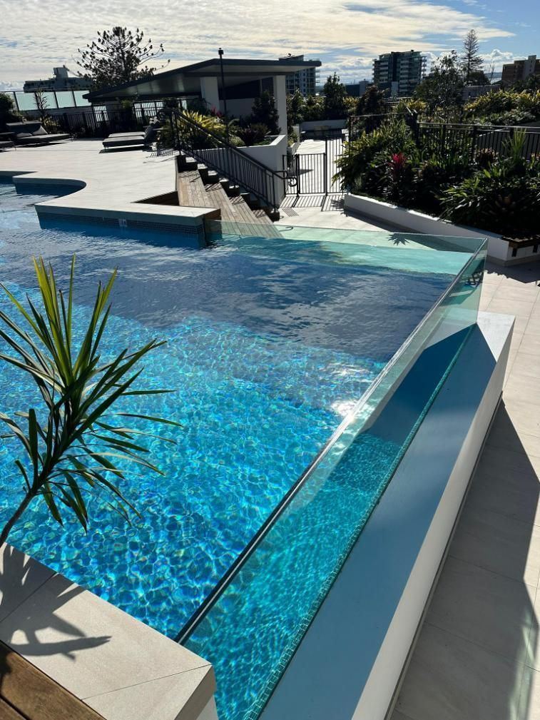 A Large Swimming Pool With A Clear Glass Fence Around It — Glass Pool Windows Australia In Brisbane, QLD