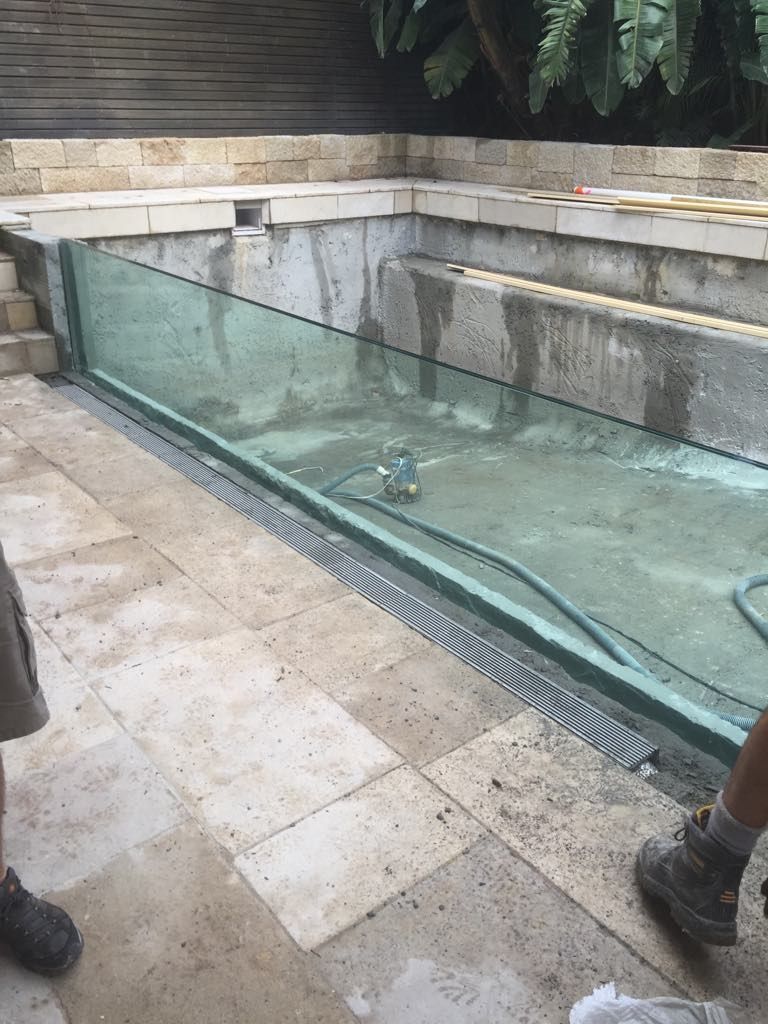 A Man Is Standing Next To A Swimming Pool With A Glass Fence — Glass Pool Windows Australia In Geelong, VIC