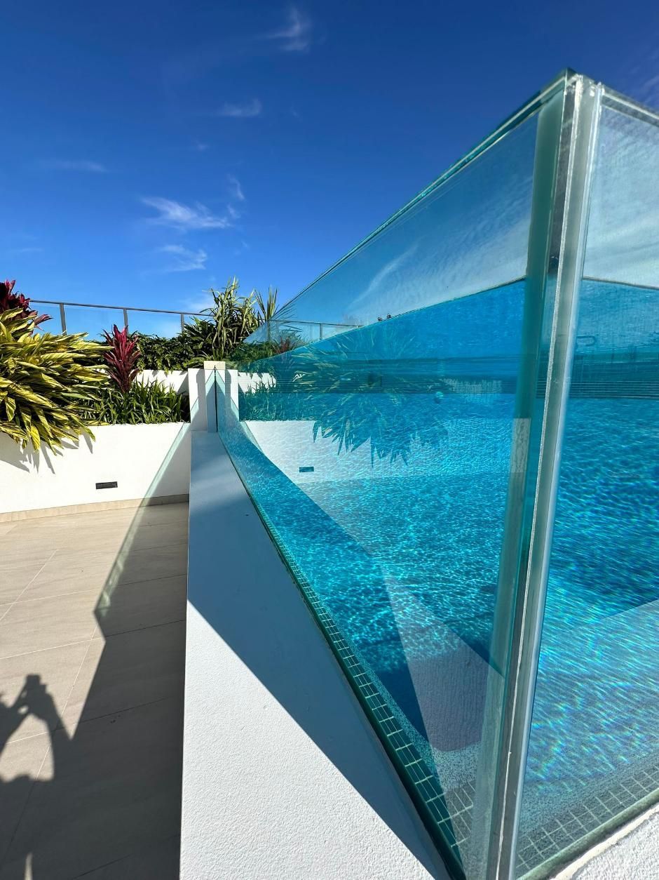 A Swimming Pool With A Clear Glass Fence Around It — Glass Pool Windows Australia In Tweed Heads, NSW