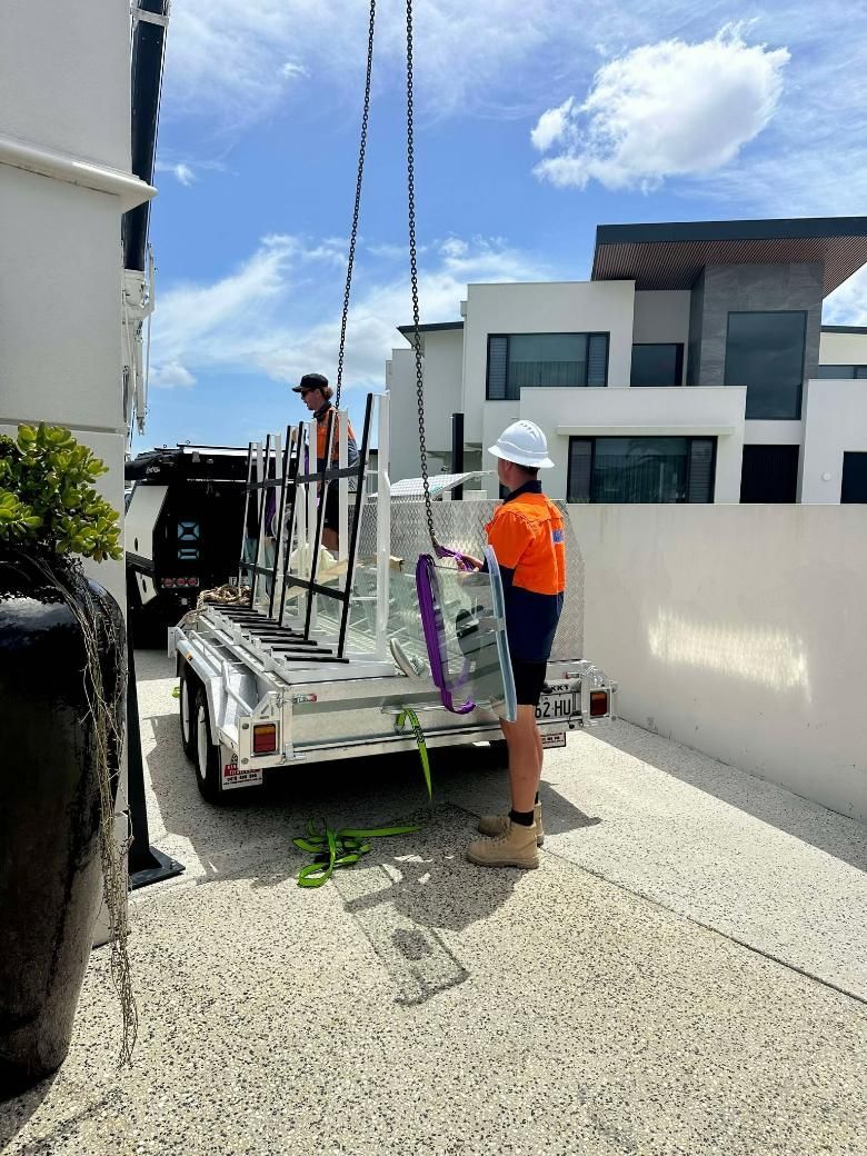 A Man Is Standing Next To A Trailer With A Crane Attached To It — Glass Pool Windows Australia In Tweed Heads, NSW