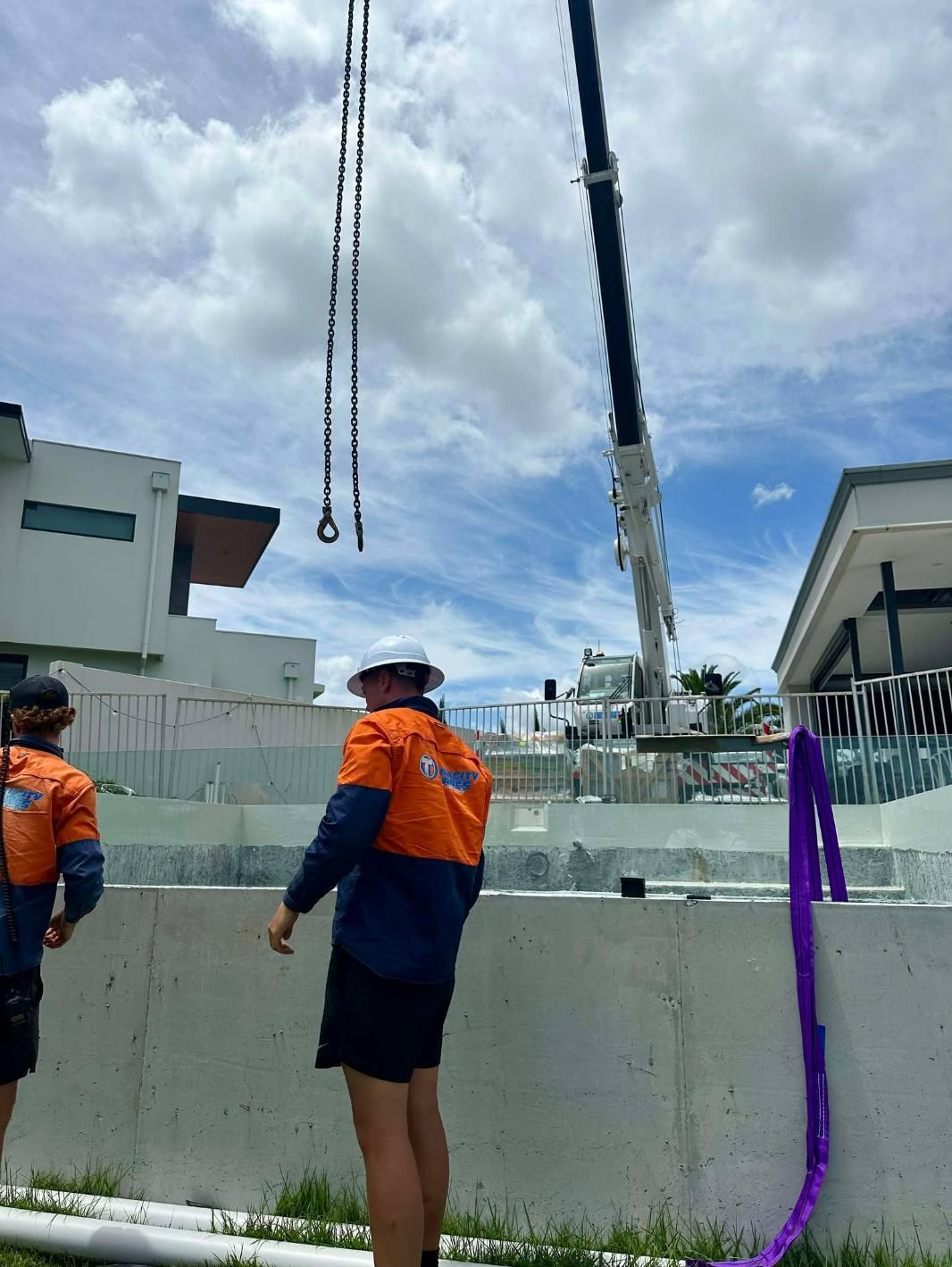 Two Construction Workers Are Standing In Front Of A Large Crane — Glass Pool Windows Australia In Canberra, ACT
