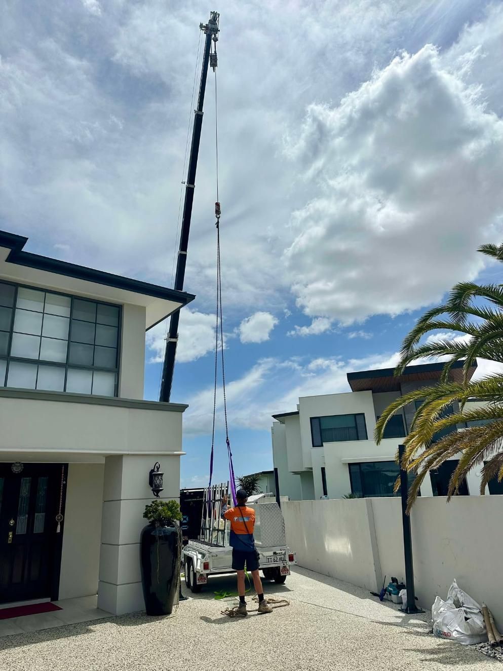 A Man Is Standing In Front Of A House With A Crane In The Background — Glass Pool Windows Australia In Canberra, ACT