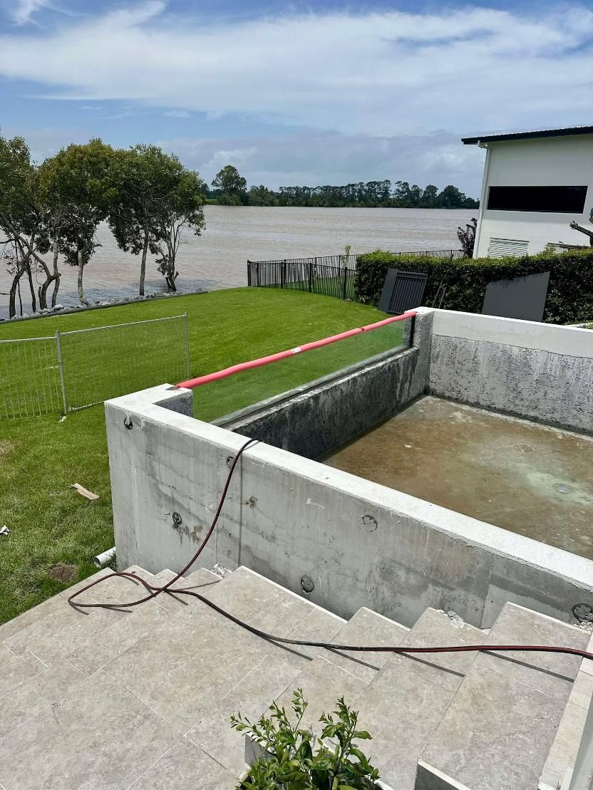 A Swimming Pool Is Being Built In A Backyard Next To A River — Glass Pool Windows Australia In Canberra, ACT