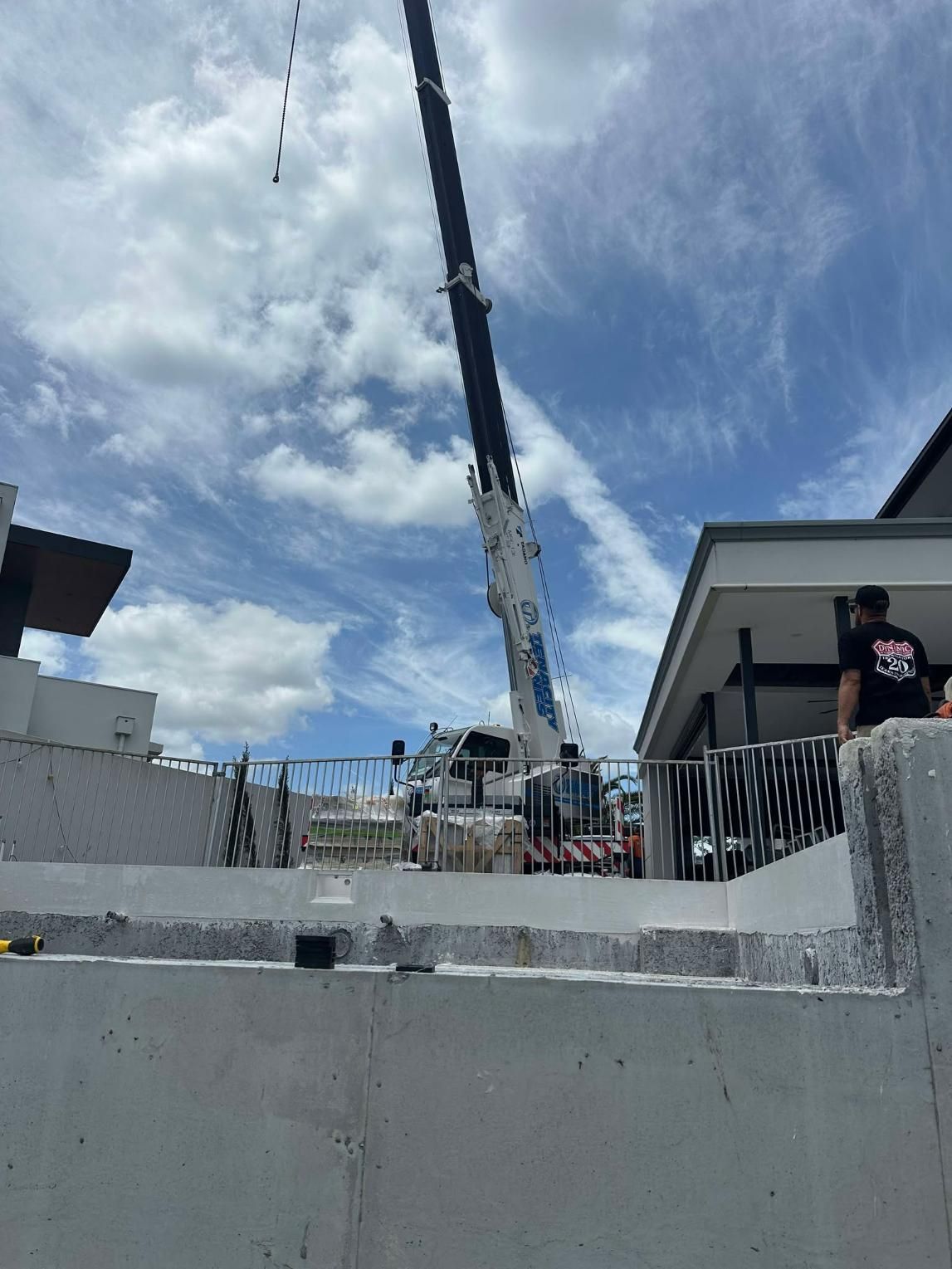 A Large Crane Is Sitting On Top Of A Concrete Wall In Front Of A Building — Glass Pool Windows Australia In Wollongong, NSW