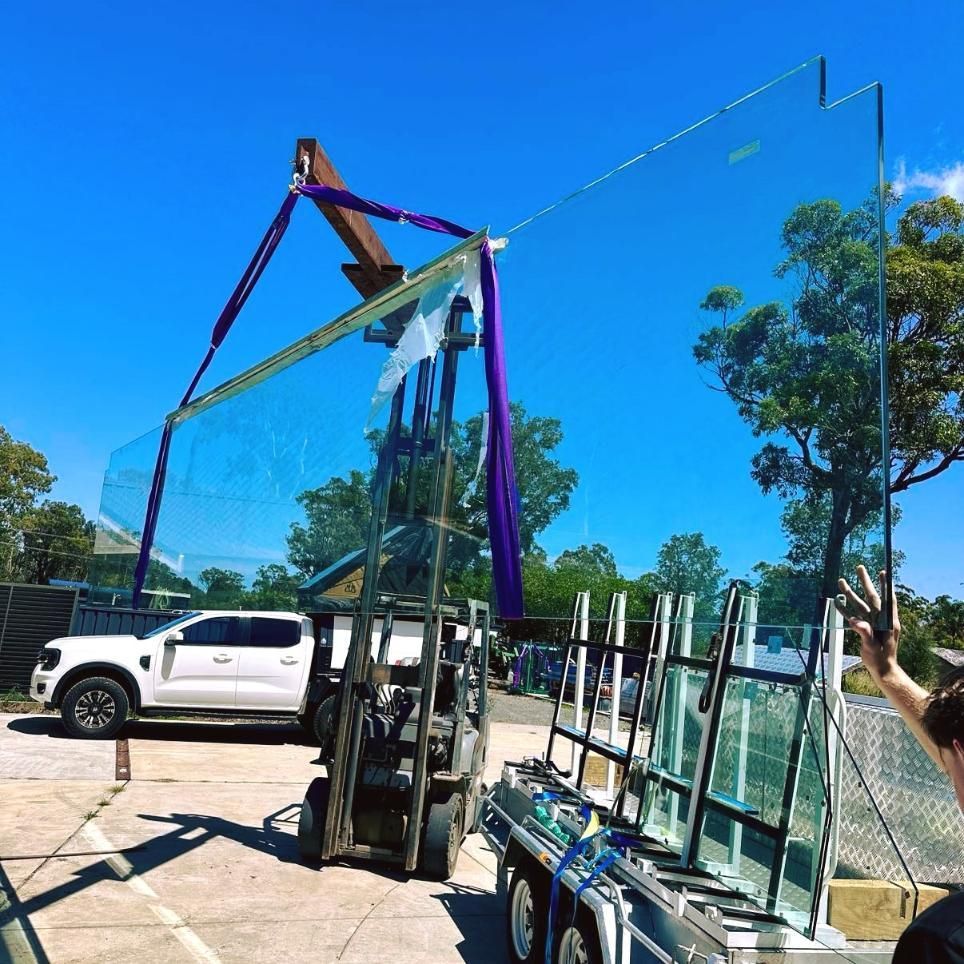 A Large Piece Of Glass Is Being Lifted By A Forklift — Glass Pool Windows Australia In Wollongong, NSW