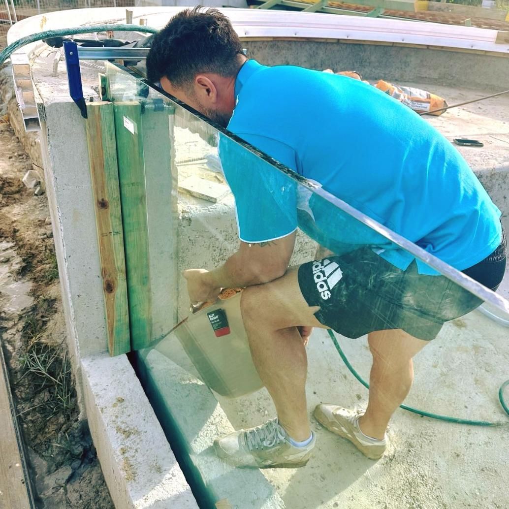 A Man In A Blue Shirt And Adidas Shorts Is Working On A Wall — Glass Pool Windows Australia In Bundaberg, QLD