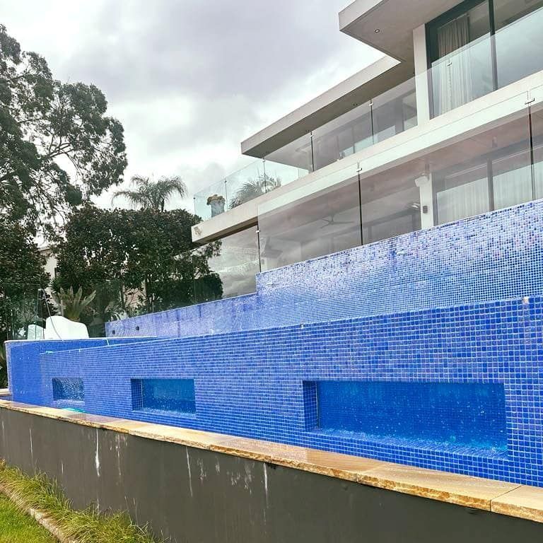 Blue Tiled Pool in Front of a Modern White Building — Glass Pool Windows Australia In Manly, NSW