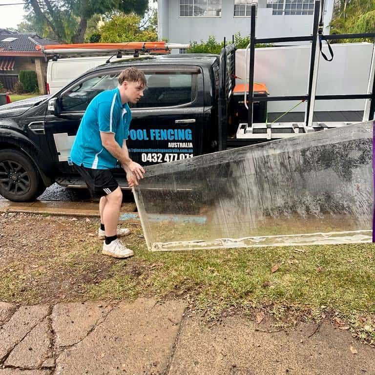 Man Carrying a Clear Glass Panel — Glass Pool Windows Australia In Broadbeach, QLD
