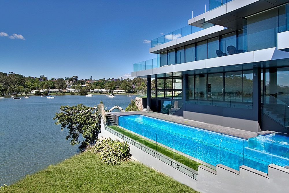 A Large House With A Swimming Pool Overlooking A Lake — Glass Pool Windows Australia In Old Bar, NSW