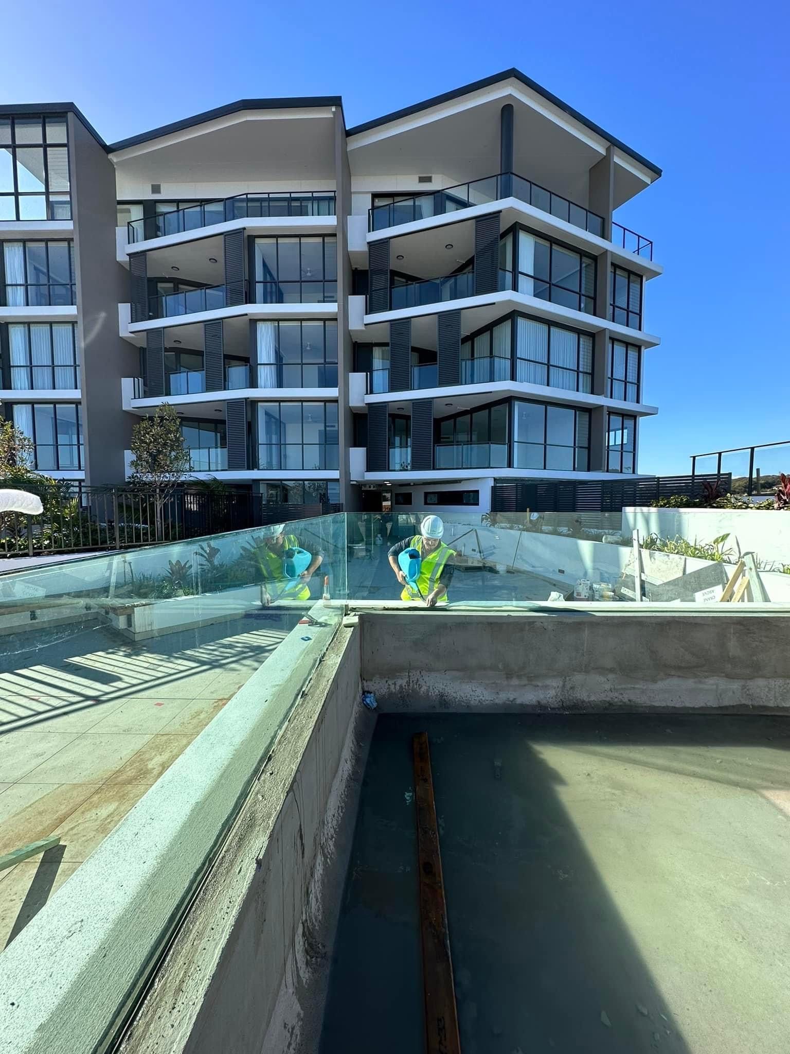 A Large Building With A Lot Of Windows And A Pool In Front Of It — Glass Pool Windows Australia In Old Bar, NSW