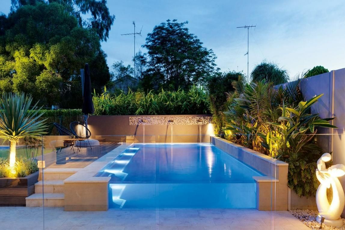 A Modern Backyard Pool Glows Blue at Night — Glass Pool Windows Australia In Palm Beach, QLD
