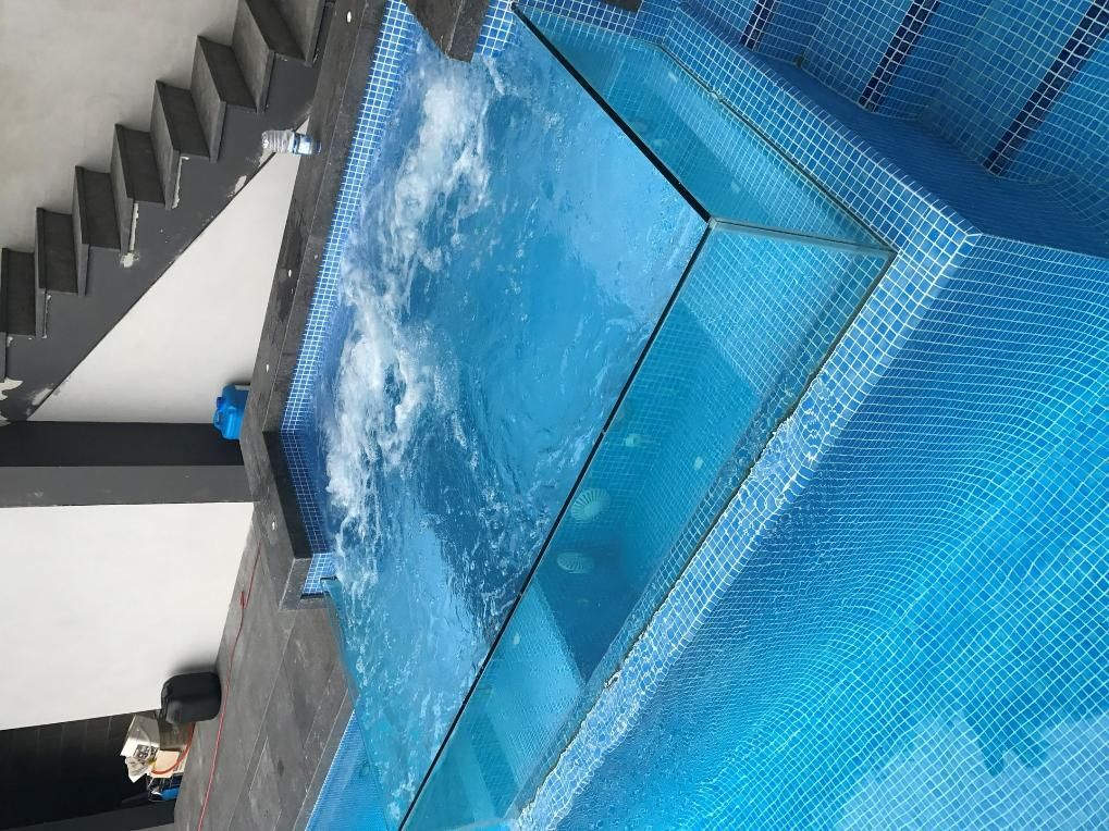 A Swimming Pool With A Glass Wall And Stairs In The Background — Glass Pool Windows Australia In Brisbane, QLD