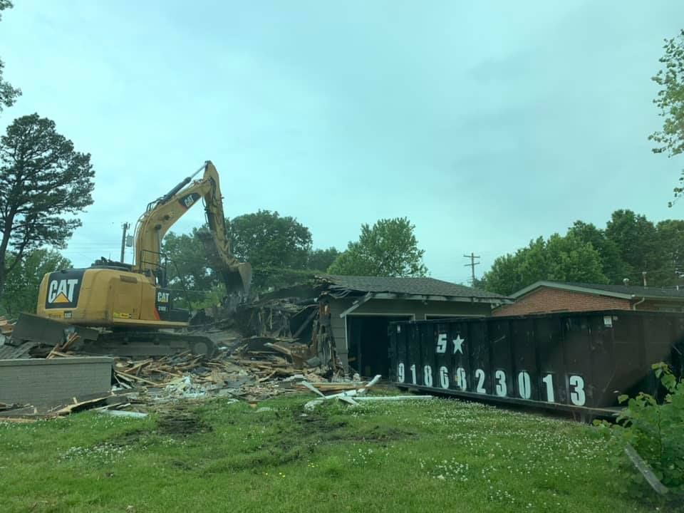 Bulldozer Demolishing a House Next to a Black Roll-Off Dumpster — Oktaha, OK — Five Star Roll-Offs Services