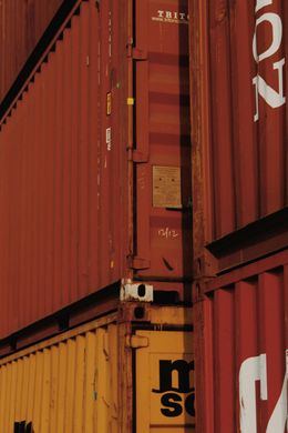 Stacked cargo containers; red, yellow, and rust-colored; outdoors.