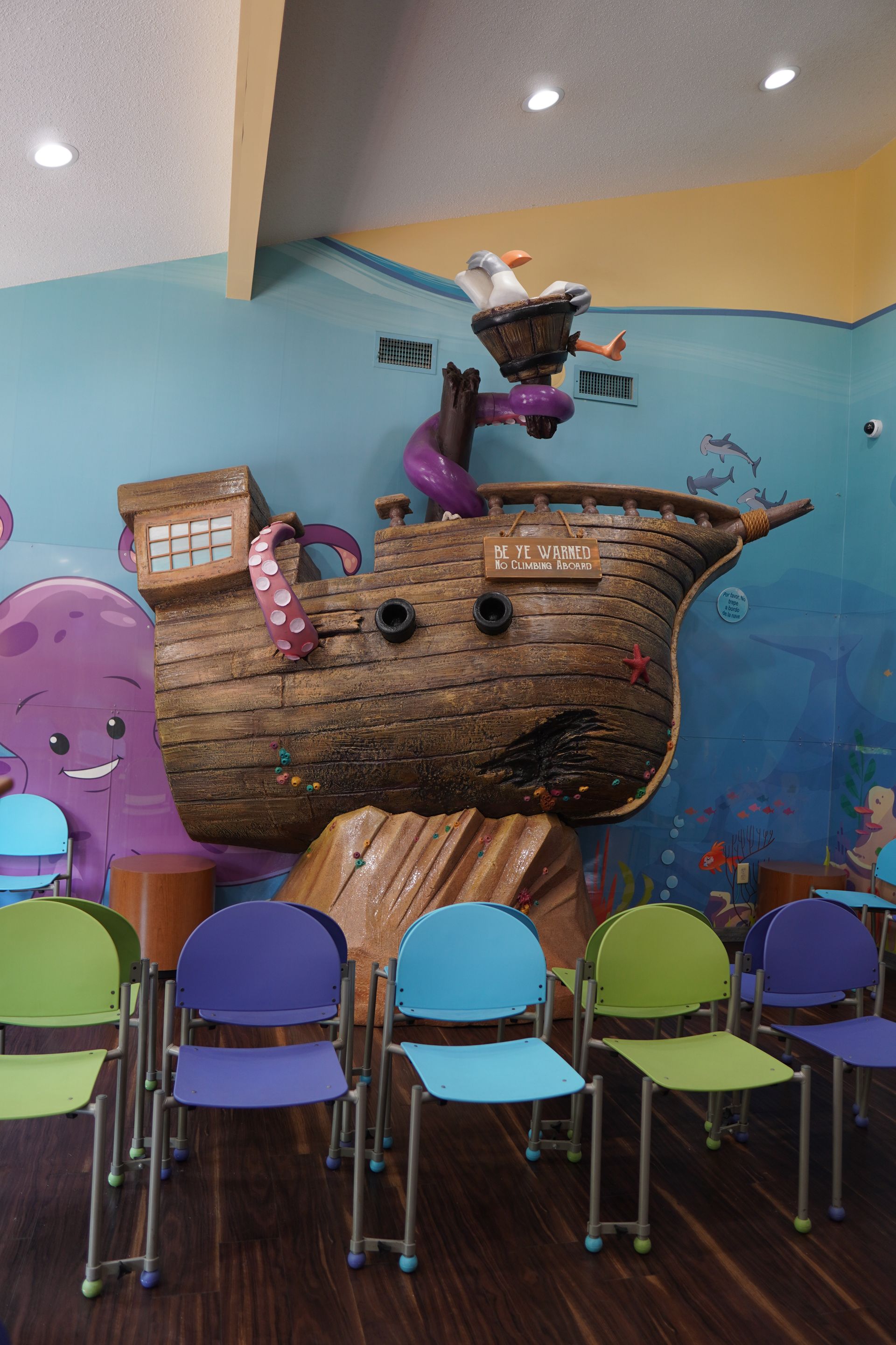 A room with chairs and a pirate ship on the wall