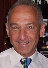 A man in a white shirt and tie is smiling for the camera.