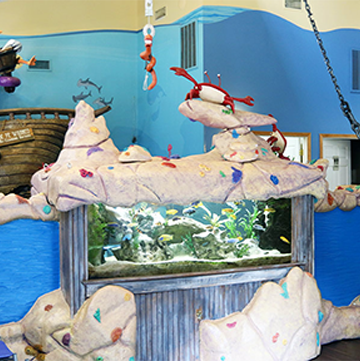 A fish tank with crabs and a ship in the background