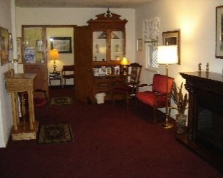 Interior room with red carpet, fireplace, antique furniture, and a partially open doorway.