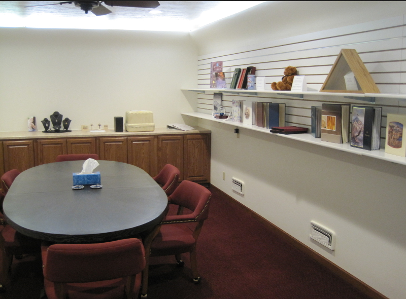 A room with a conference table, shelves with items, and cabinets.