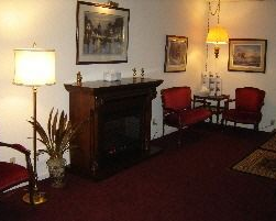Cozy room with fireplace, red chairs, and lamps; artwork hangs on the wall.