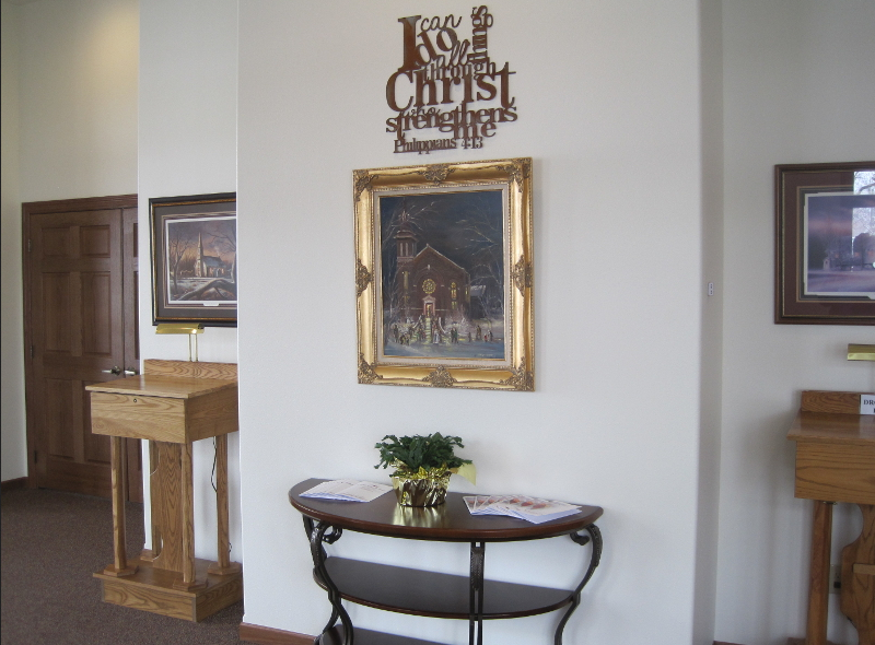 Hallway with artwork, table, wooden stands, and a sign that reads