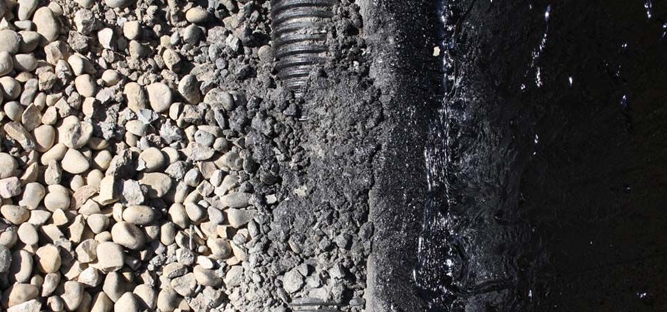 black tubing covered in gravel and grey rocks