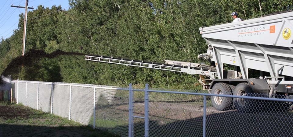 truck pouring dirt in backyard in preparation for grass installation