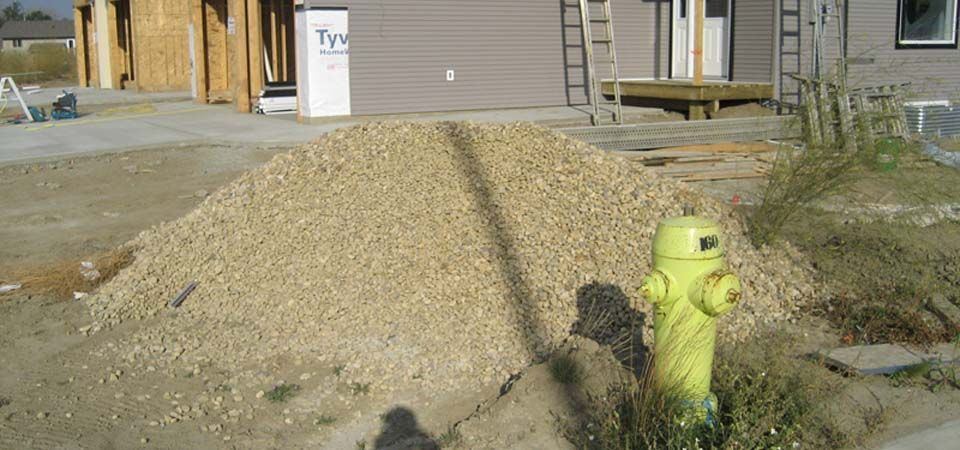 bright yellow fire hydrant in yard filled with beige gravel and dirt