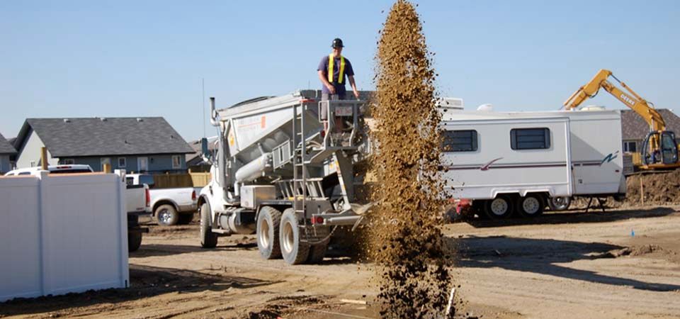 worker standing atop large dirt truck