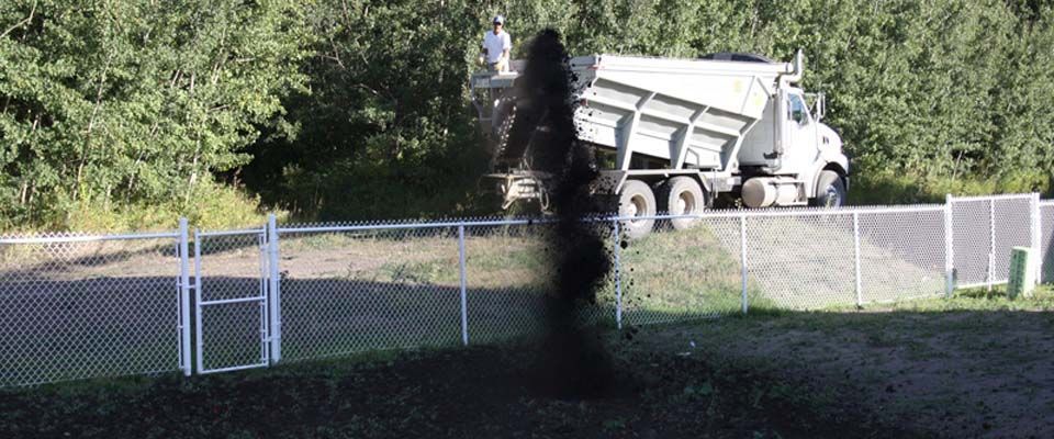 white truck pouring dirt in front yard to prepare for grass laying