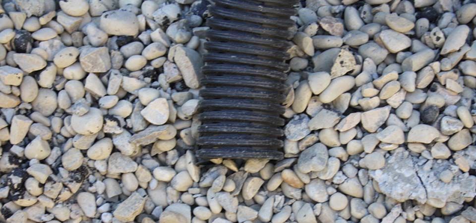 black tubing surrounded by grey and beige rocks and gravel