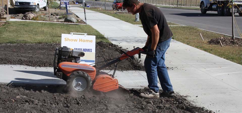 worker using machinery to flatten dirt for landscaping job