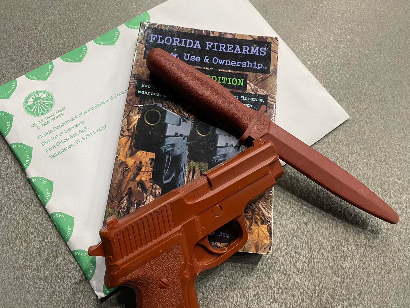 Brown toy gun and knife atop a book about Florida firearms.
