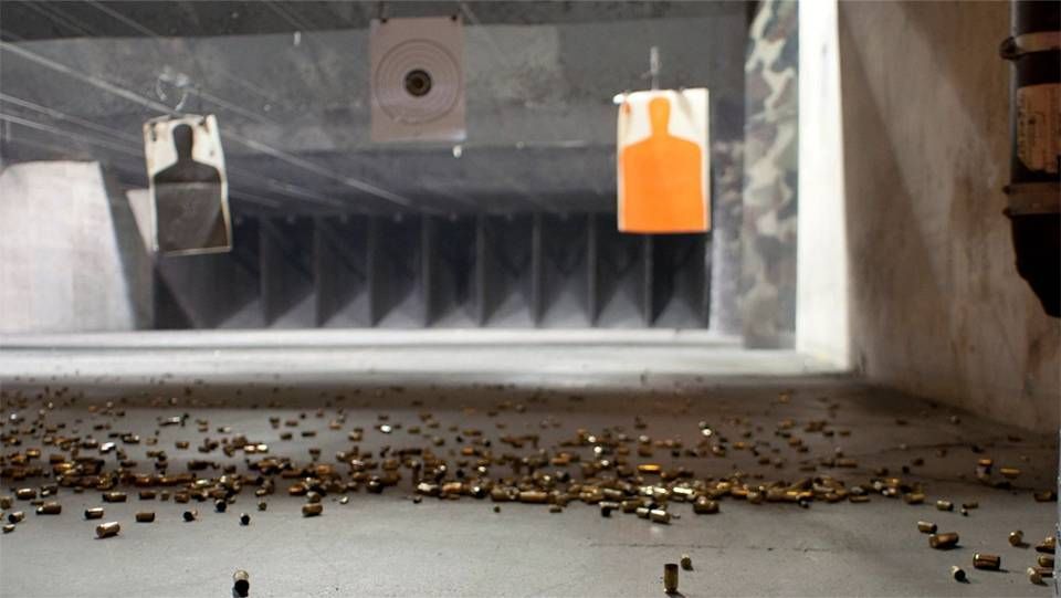 Shooting range with hanging targets. Brass shell casings litter the floor.
