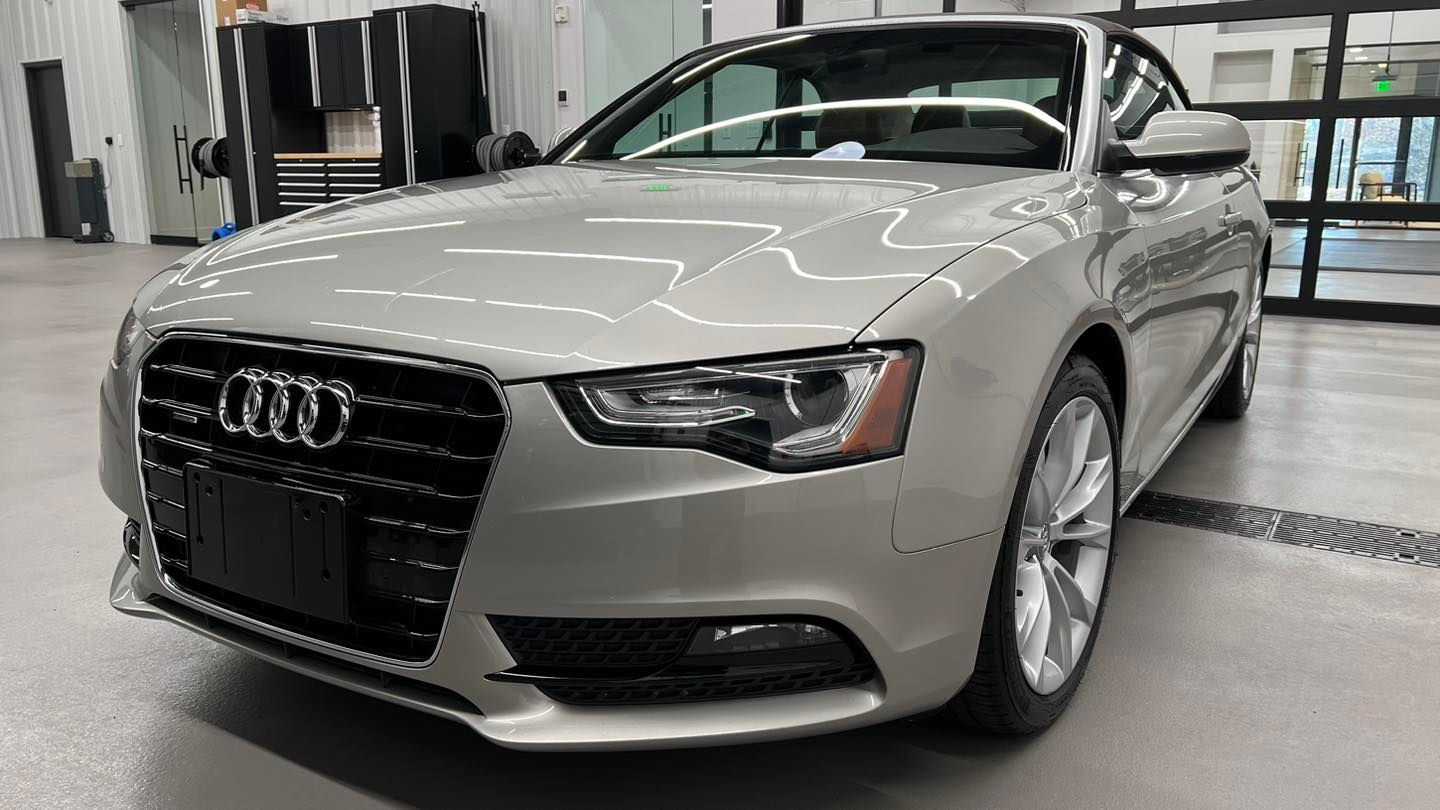 A silver audi a5 convertible is parked in a garage.