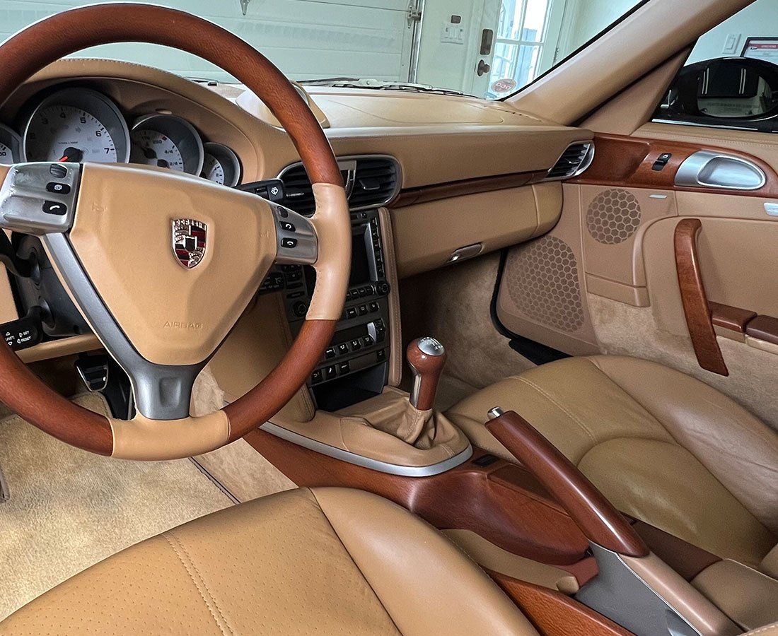 Tan and brown Porsche interior with leather seats, steering wheel, and wooden accents.