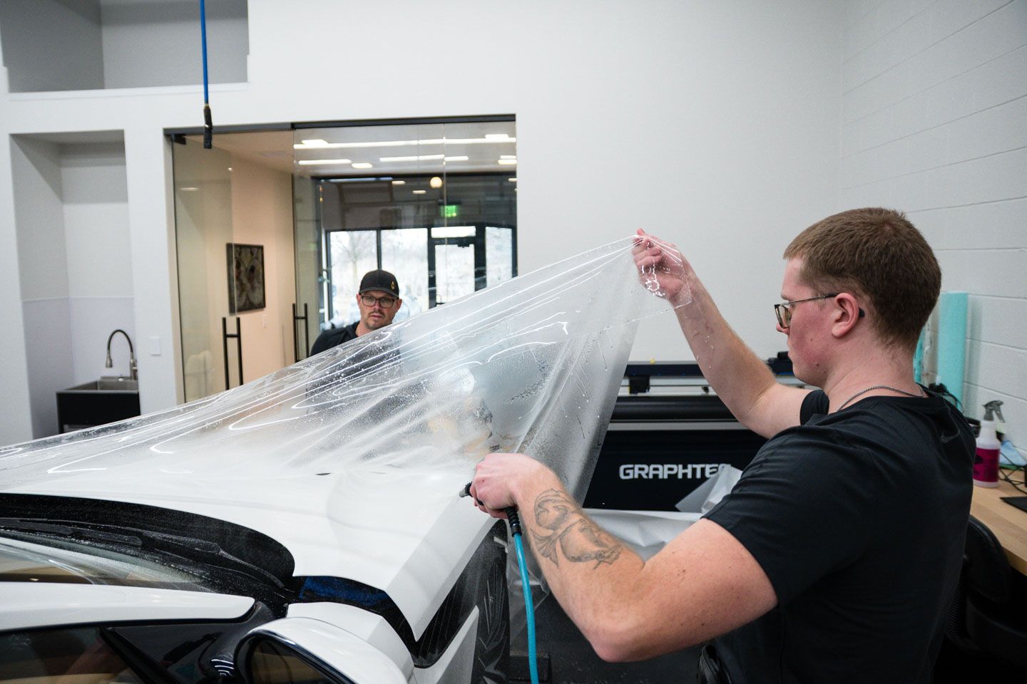 Yellow Audi, red Ferrari, and black car parked in front of a garage with a white door.