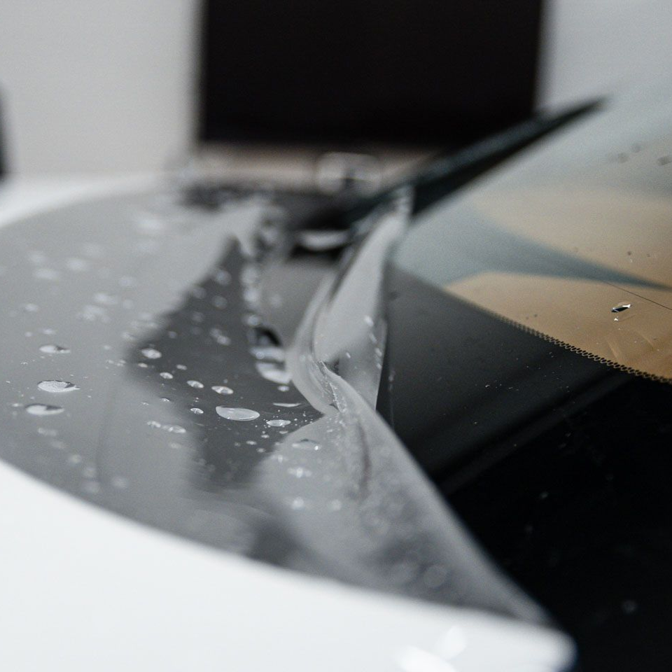 Person spraying red liquid from a foam cannon onto a car in a garage.
