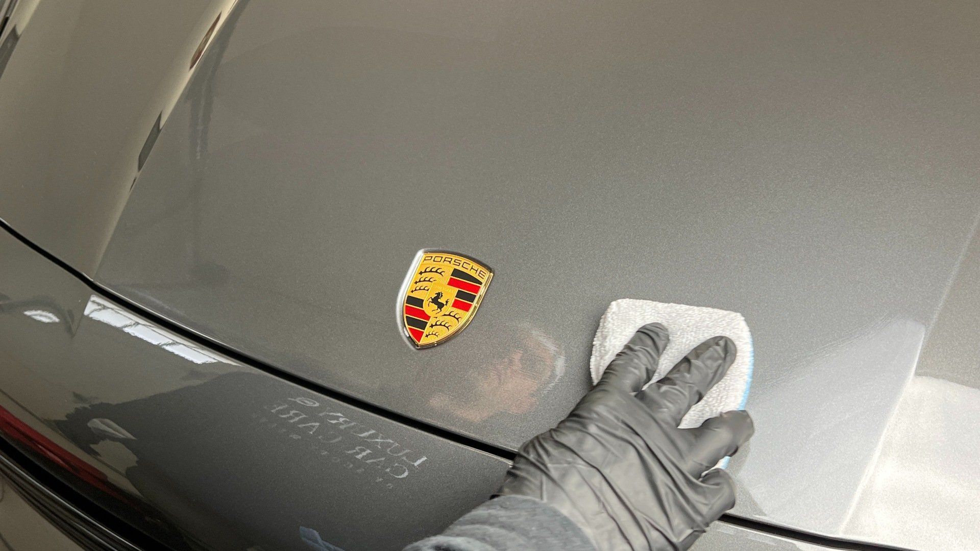 a person is cleaning the hood of a porsche car .