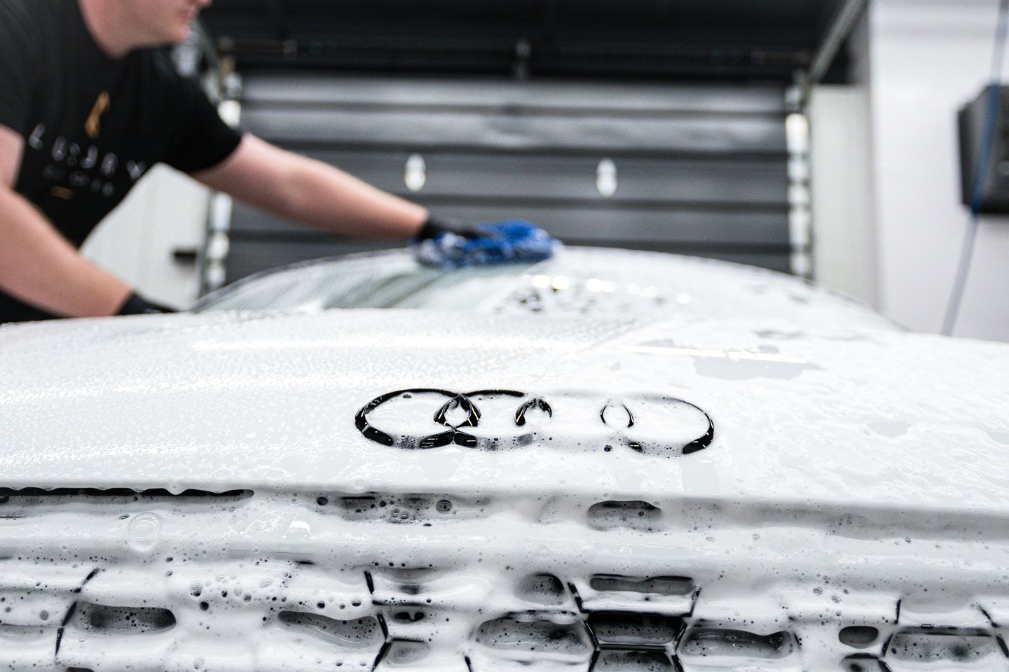 A man is washing the hood of an audi car.
