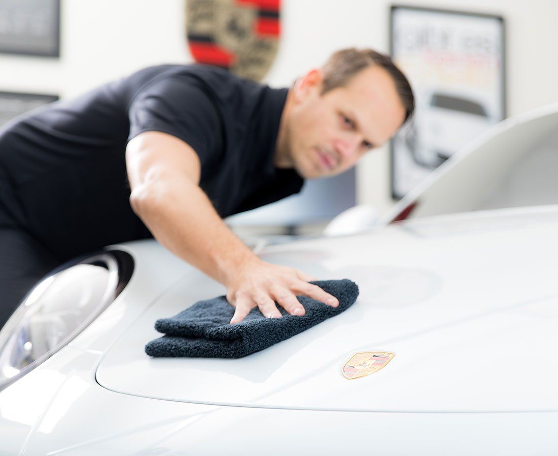 a man is cleaning a white car with a towel