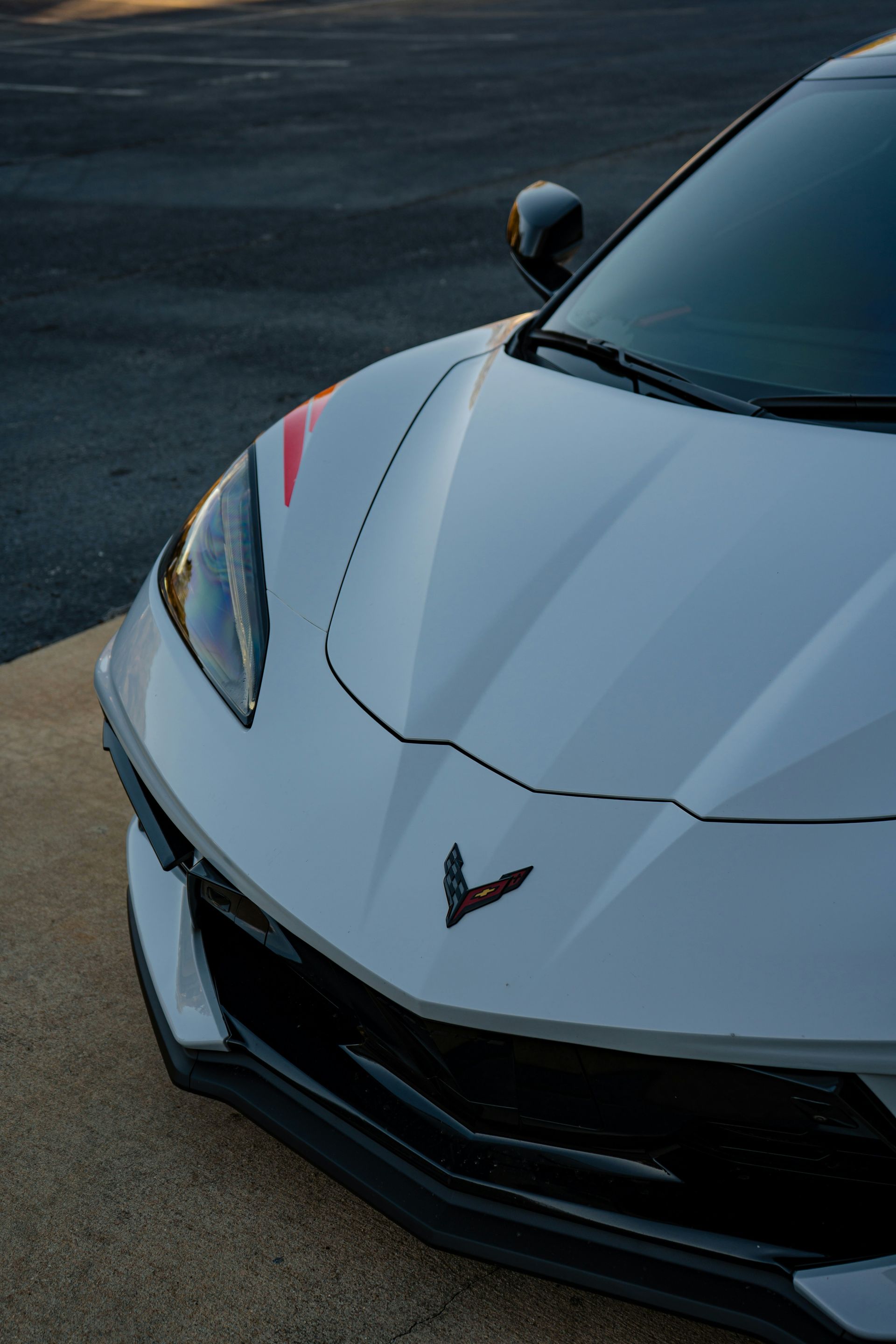 White Chevrolet Corvette sports car, angled view, with red stripe detail on hood.