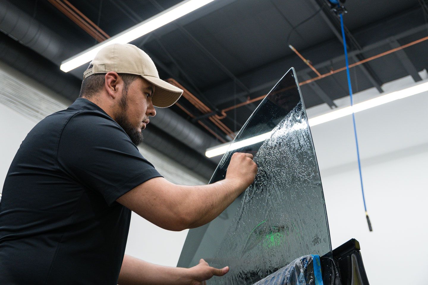 A person is applying tinted glass to a car windshield.