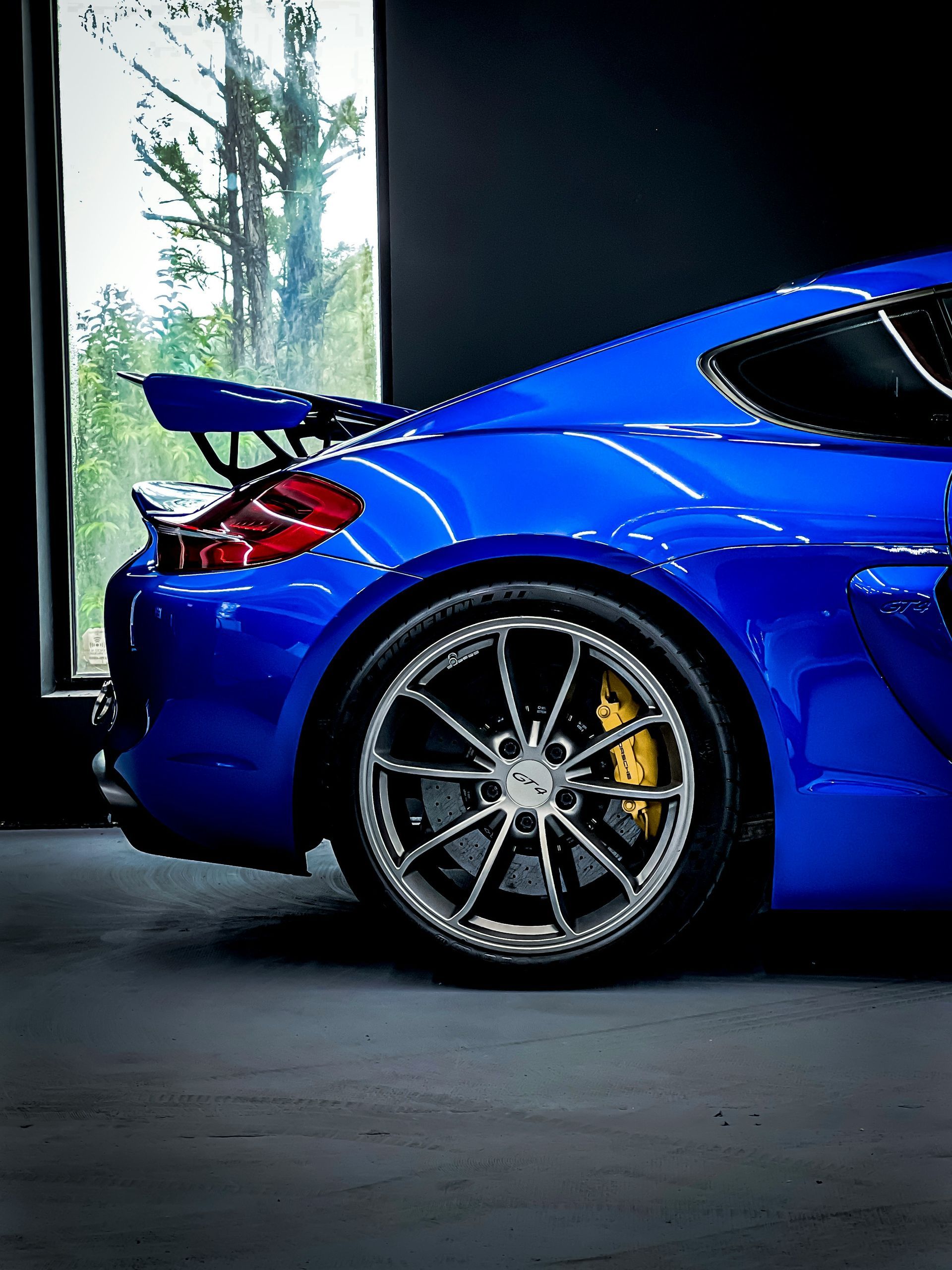 Yellow Audi, red Ferrari, and black car parked in front of a garage with a white door.