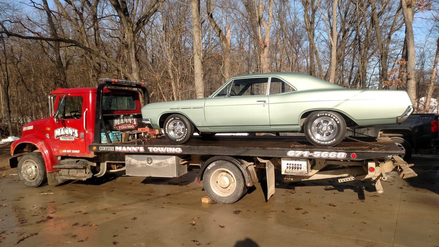 a green car is sitting on top of a tow truck .