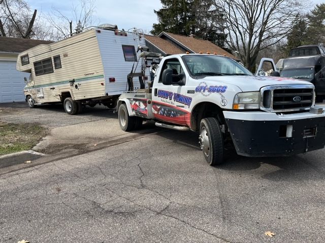 a tow truck is towing a camper down a street .
