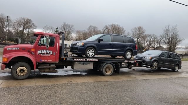 a tow truck is carrying a minivan and a car .