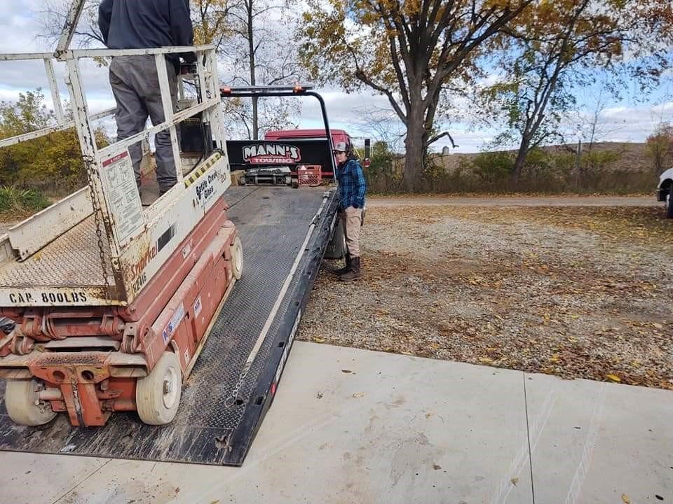 a man is standing next to a scissor lift in a parking lot .