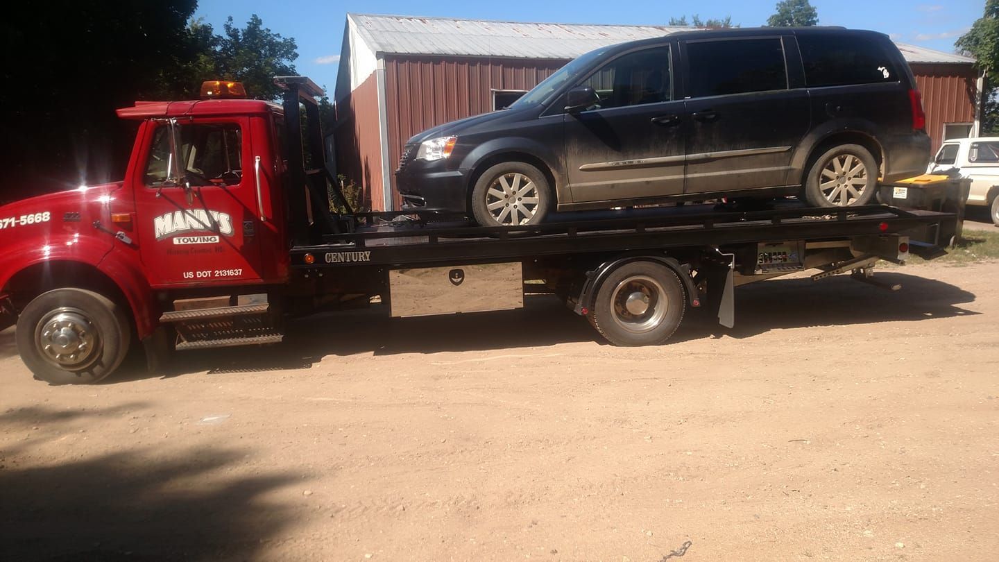 a tow truck is carrying a minivan on top of it .